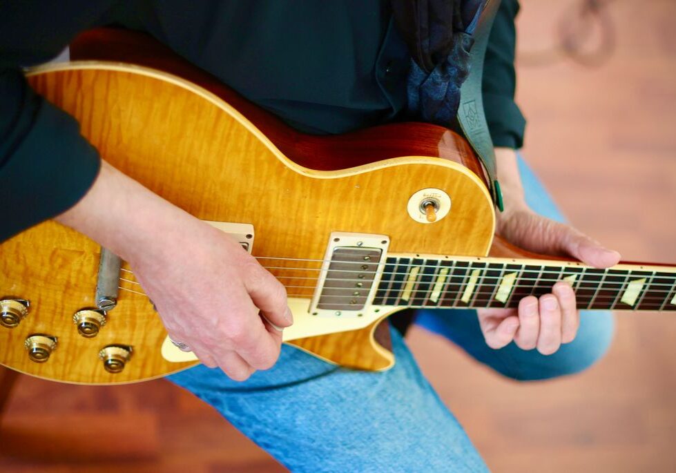 Sie sehen einen Gitarristen, der seine E-Gitarre hält und gleich spielen wird.